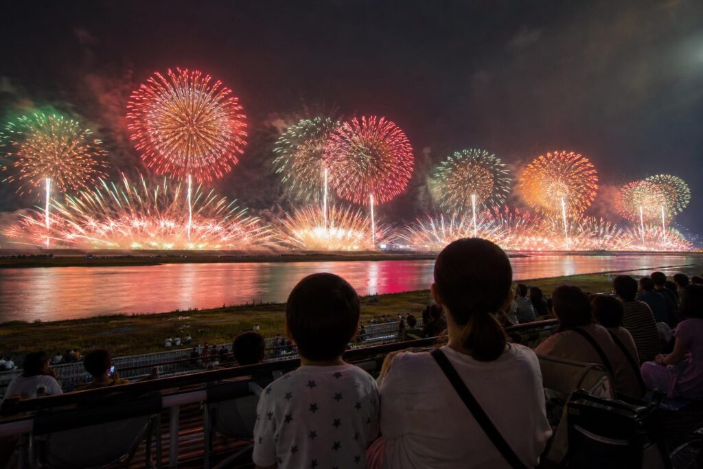 荒川の両岸に広がる大規模な花火を眺める親子